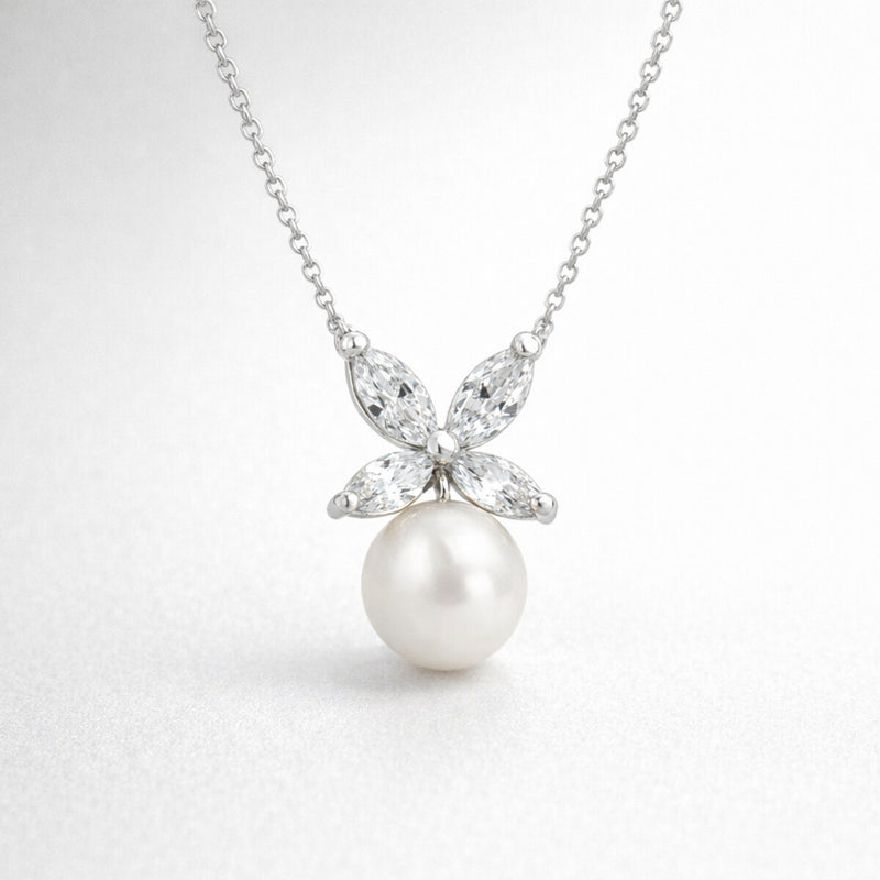 Studio view of a silver tone butterfly shaped pendant featuring marquise cut cubic zirconia stones forming the wings and a suspended round white pearl.