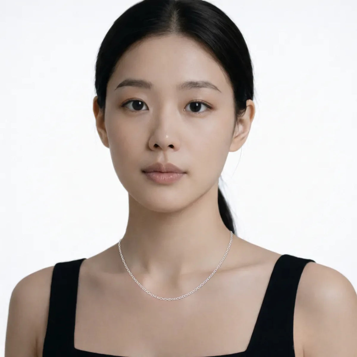 Model shot captures a silver tone classic cable chain necklace, styled with a black sleeveless dress so the chain drapes cleanly along the collarbone.