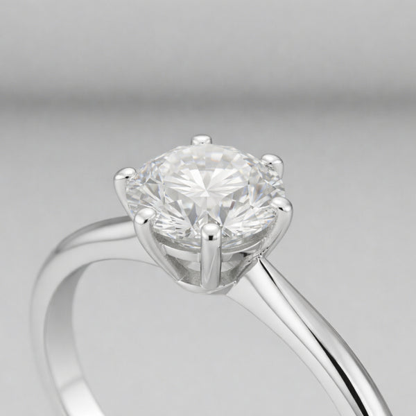 Side profile close up view of the classic solitaire cubic zirconia ring focusing on the raised prong setting, polished silver tone band and the round cut center stone.
