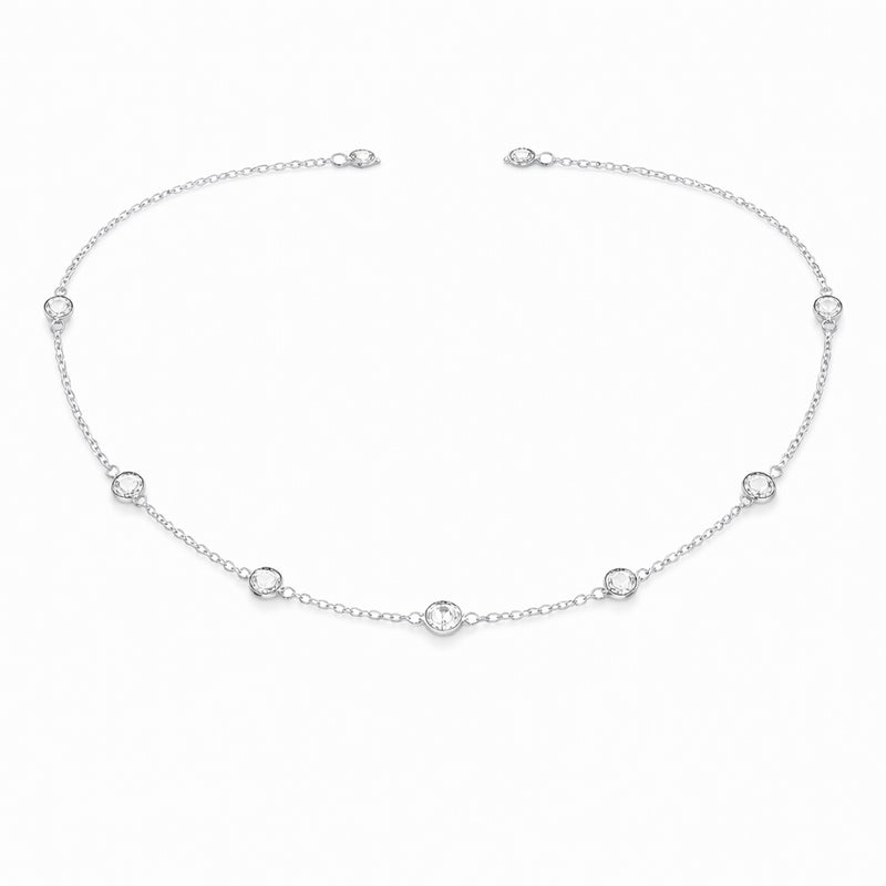 Angled studio view of the silver tone station necklace highlighting the refined chain links and round bezel set stone details.