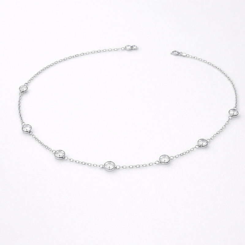 Styled lifestyle image of a station necklace worn close to the collarbone, showcasing the elegant placement of bezel set stones in silver tone.
