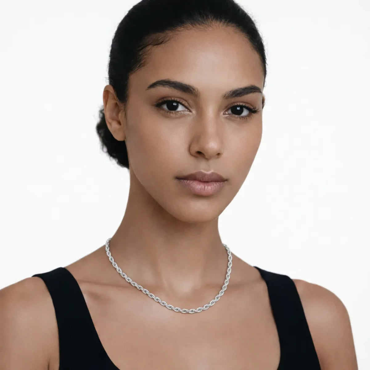 On-model portrait highlights a silver tone classic twisted chain necklace, styled with a black tank neckline so the chain drapes cleanly along the collarbone.