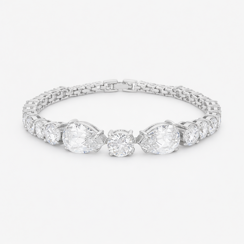 Studio view of a tennis bracelet featuring pear and round cut cubic zirconia set in rhodium plated brass.