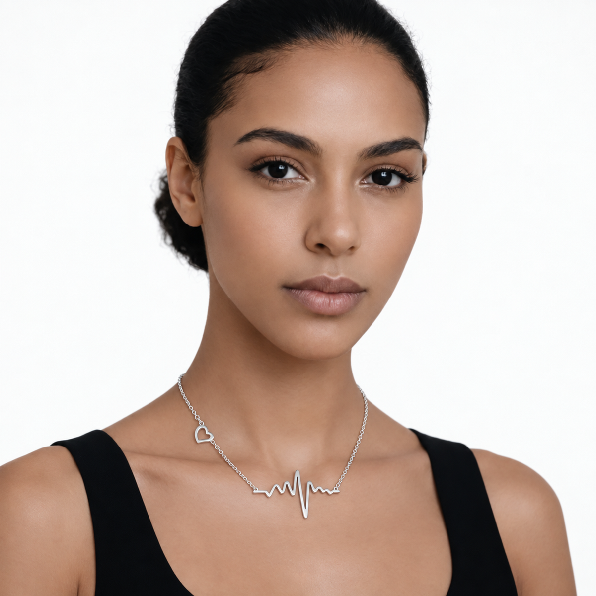 Model wearing heartbeat and heart necklace in silver tone with a black top.
