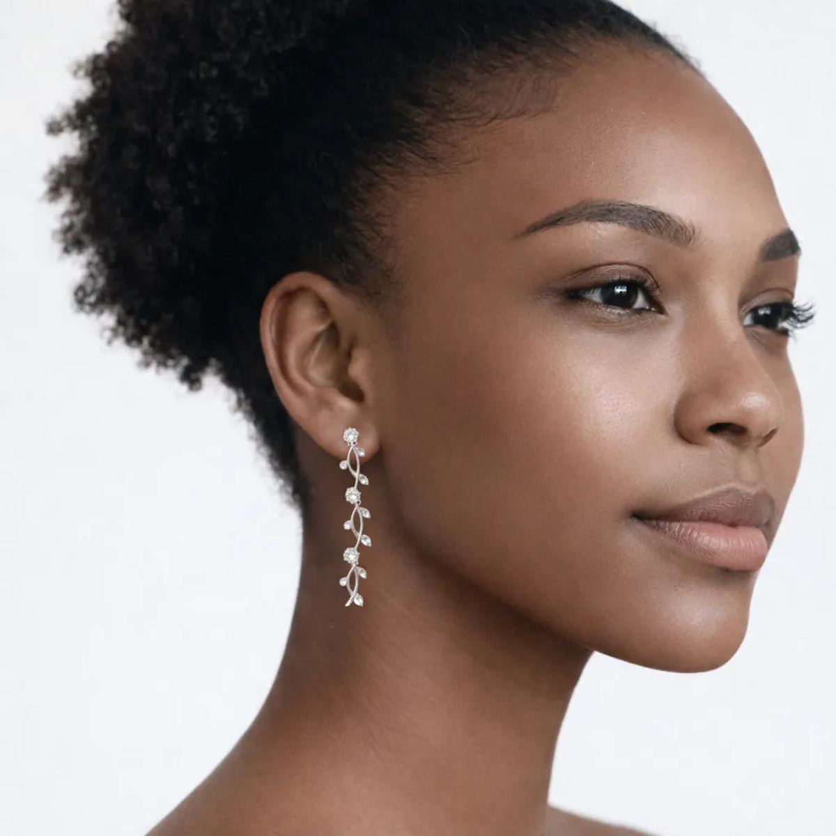 On-model portrait highlights leaf motif drop earrings with cubic zirconia, styled with bare shoulders so the earrings frame the face with high-polish shine.