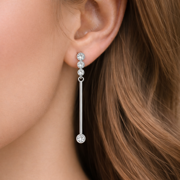 Linear drop earring worn on the ear, showing slim proportions and modern elegant appearance.
