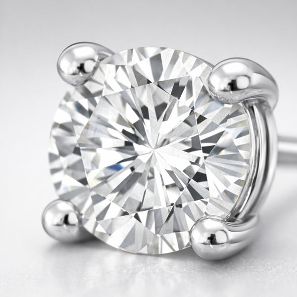 Detailed close up of a round silver tone stud earring showcasing the brilliant cubic zirconia stone and smooth four prong metal setting.