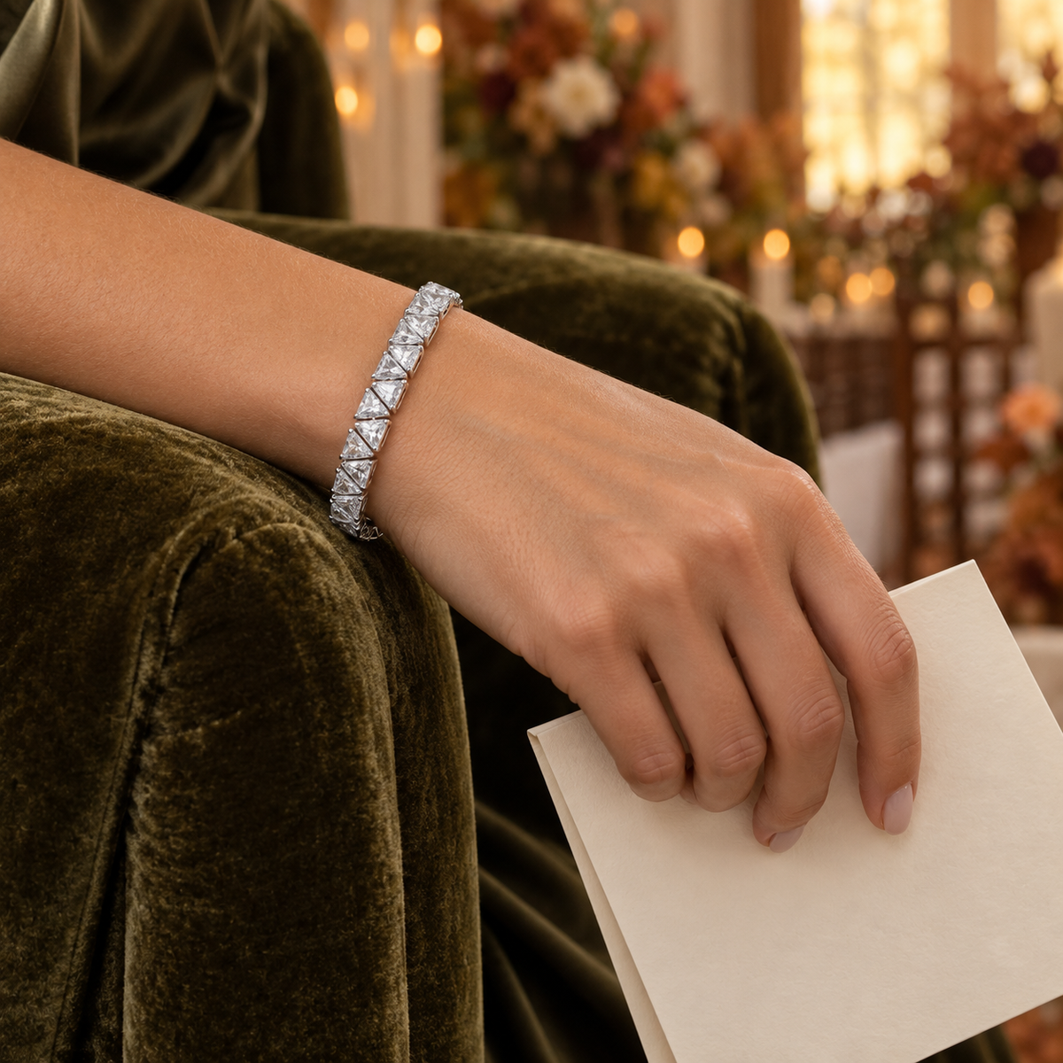 Silver-tone cubic zirconia tennis bracelet worn on a wrist holding a cream ceremony program.