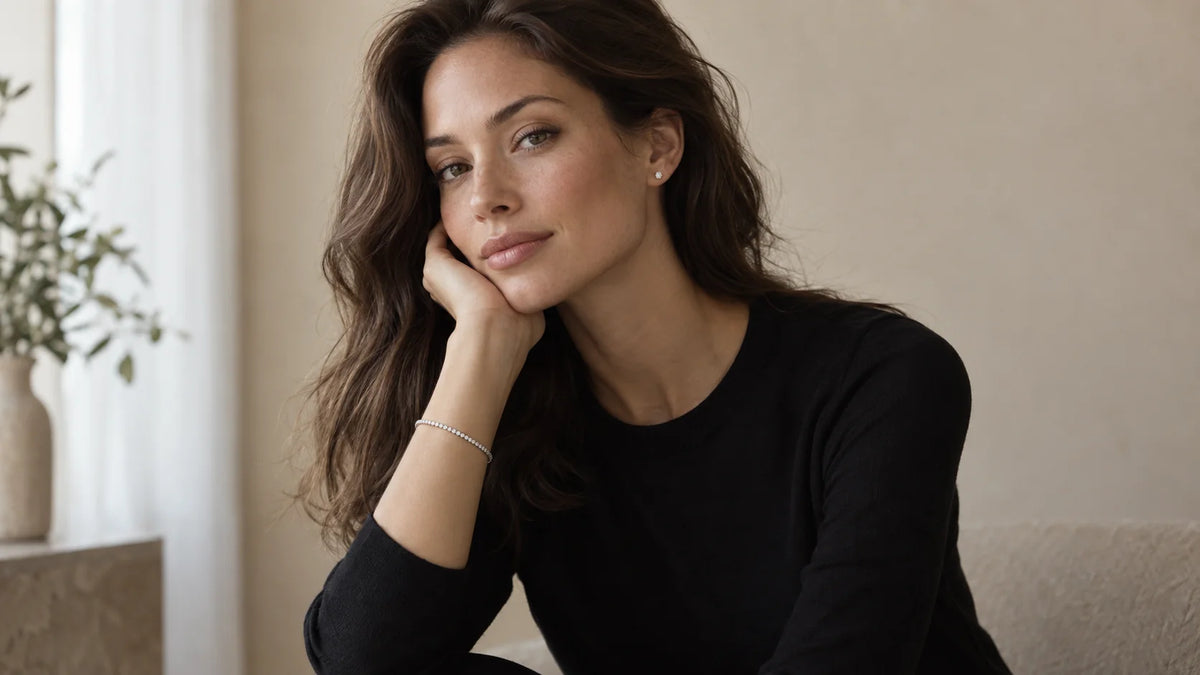Woman in a black crewneck top wearing a round silver-tone cubic zirconia stud and a narrow silver-tone cubic zirconia tennis bracelet
