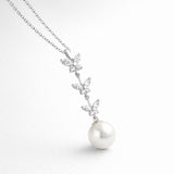 Angled studio view highlighting the vertical butterfly arrangement with marquise cut cubic zirconia stones and a suspended pearl.