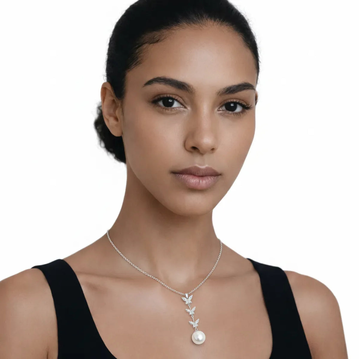 On-model portrait highlights a butterfly drop cubic zirconia and pearl pendant, styled with a black scoop-neck top to keep the pendant centered at the neckline.
