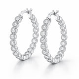 Studio side view of classic silver tone hoop earrings featuring multiple round cubic zirconia stones evenly set along the hoop.
