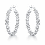 Angled studio view of silver tone hoop earrings highlighting the hinged closure and evenly spaced round cubic zirconia settings.