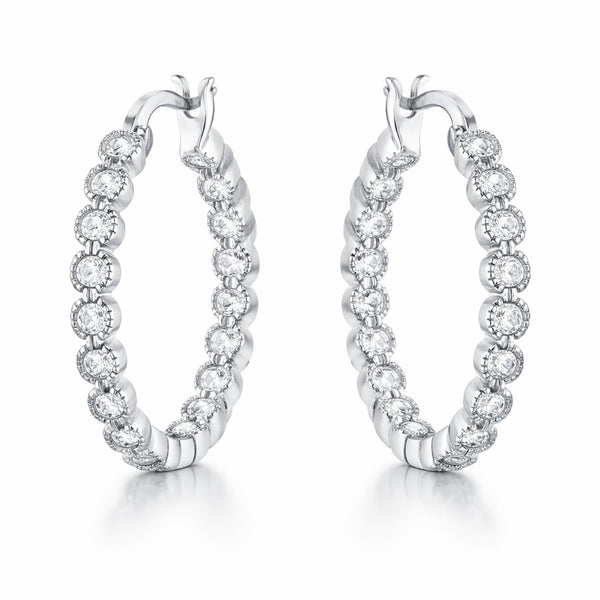 Angled studio view of silver tone hoop earrings highlighting the hinged closure and evenly spaced round cubic zirconia settings.