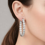 Hoop earrings worn on the ear, showcasing the elegant circular design, sparkling round cubic zirconia stones, and polished silver tone finish.