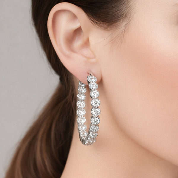 Hoop earrings worn on the ear, showcasing the elegant circular design, sparkling round cubic zirconia stones, and polished silver tone finish.
