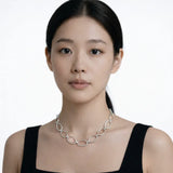 Model shot captures a silver tone classic oval link chain necklace, styled with a black sleeveless dress so the chain drapes cleanly along the collarbone.
