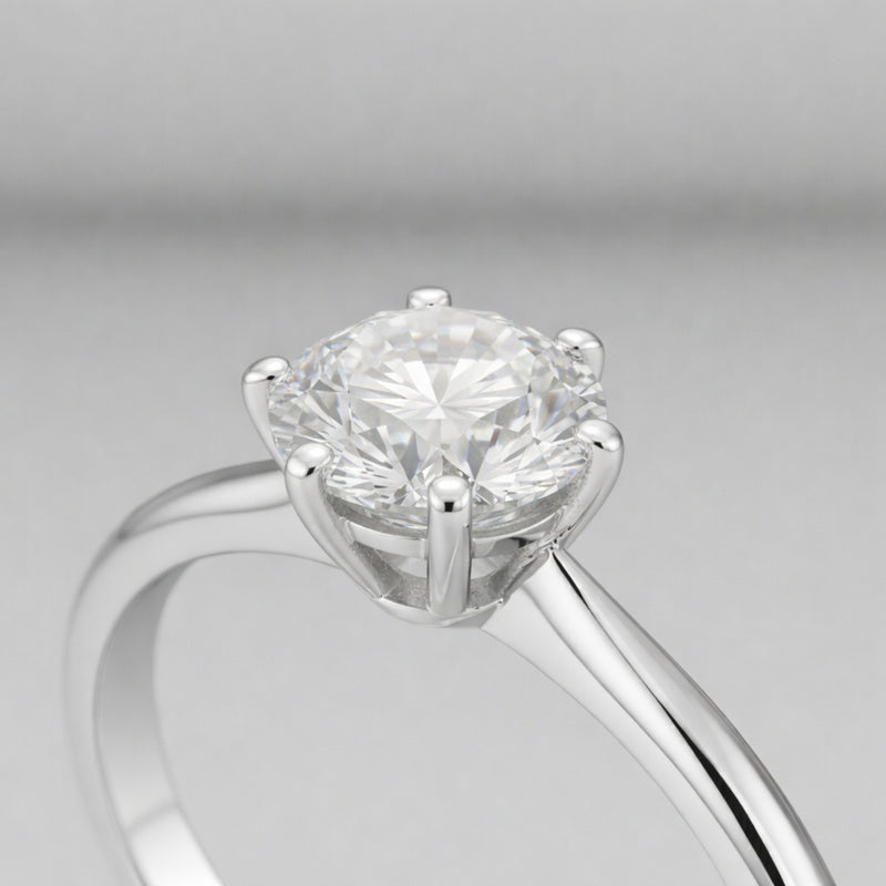 Side profile close up view of the classic solitaire cubic zirconia ring focusing on the raised prong setting, polished silver tone band and the round cut center stone.