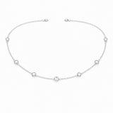 Angled studio view of the silver tone station necklace highlighting the refined chain links and round bezel set stone details.