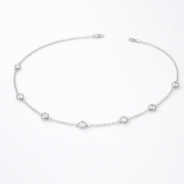 Styled lifestyle image of a station necklace worn close to the collarbone, showcasing the elegant placement of bezel set stones in silver tone.