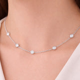 Detail view of the silver tone station necklace worn on the neck, highlighting the bezel set stone spacing and polished metal finish.
