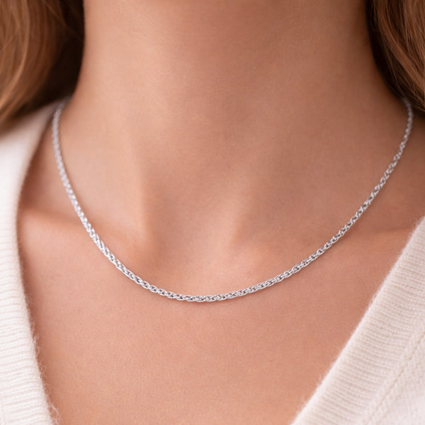 Lifestyle image of a twisted chain necklace worn on the neck, showcasing the tightly twisted silver tone structure and modern appearance.