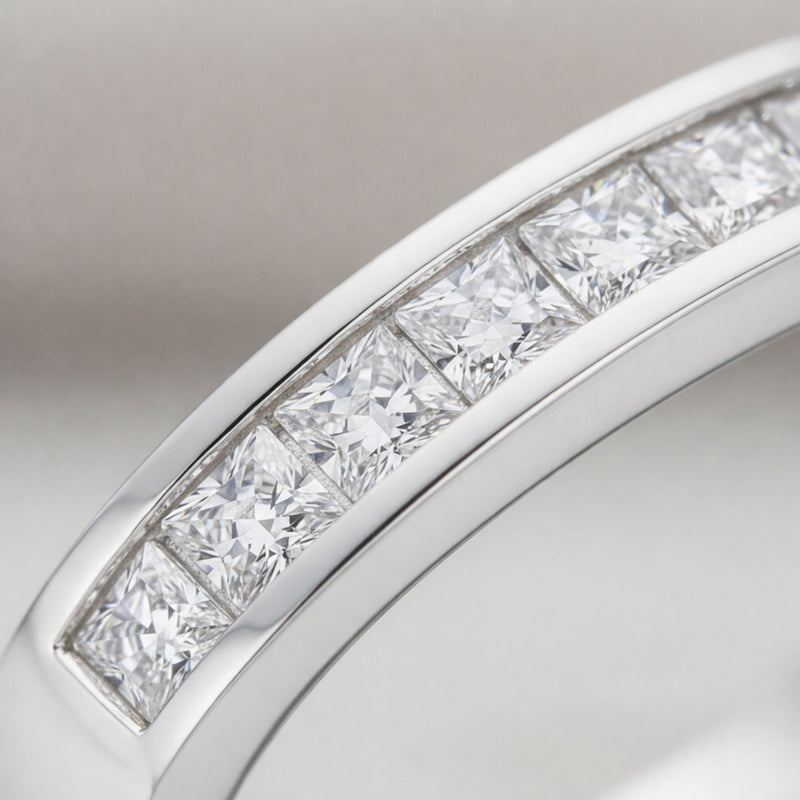Detailed close up of channel set cubic zirconia stones arranged in a straight row within a polished Silver Tone band.