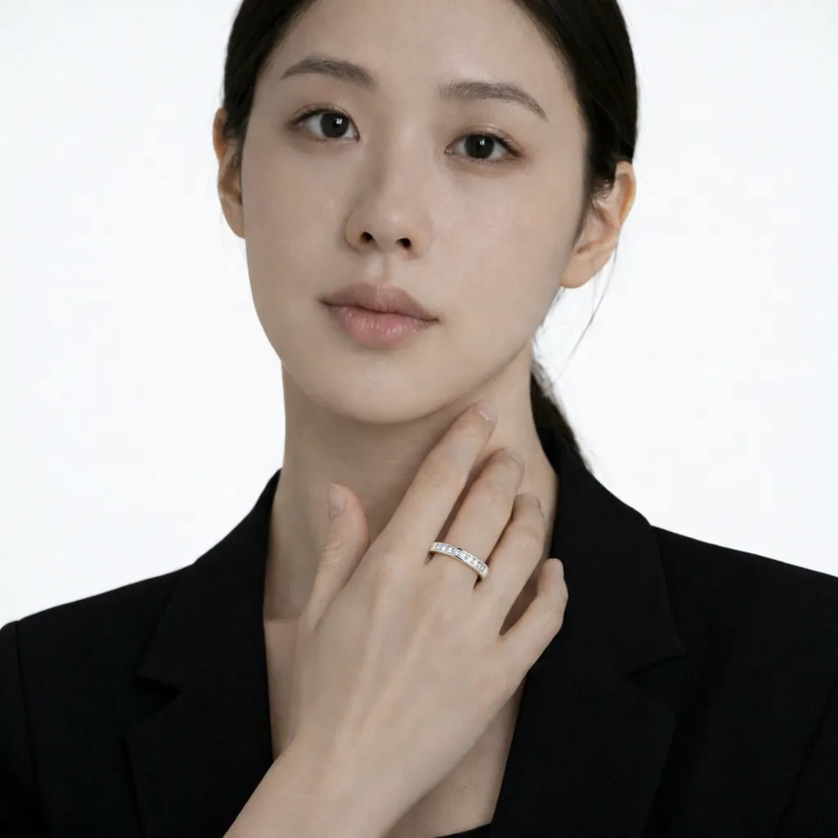 Model shot captures a silver tone diamond style rings with cubic zirconia, styled with a short-sleeve black dress so the ring sparkles along the fingertips.
