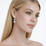 Model view showcases silver tone drop hoop earrings with cubic zirconia, styled with bare shoulders so the earrings frame the face with high-polish shine.