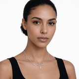 Model wearing heartbeat and heart necklace in silver tone with a black top.