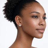 Model wearing jenny round clear stone stud earrings in silver tone with a neutral off-shoulder top.