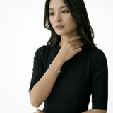 Model shot captures a slim vine bracelet of marquise cubic zirconia leaves in silver tone resting against a black dress, the line draping softly across the wrist.