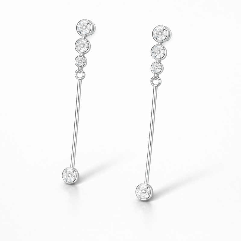 Close up side view of linear drop earrings featuring round cut cubic zirconia stones in a silver tone setting.