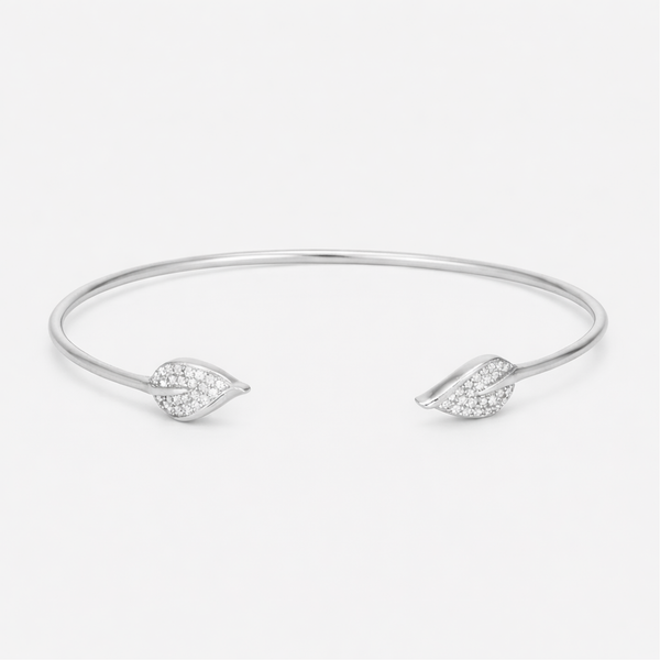 Front view of an open silver tone cuff bracelet featuring a smooth polished surface and cubic zirconia accents on both ends.