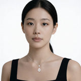Model shot captures a silver tone pear shaped drop cubic zirconia pendant, styled with a black square-neck dress so the pendant stays centered at the neckline.