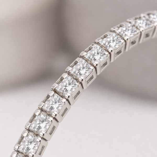 Close-up of clear square stones and individual silver-tone settings on a curved bracelet section.