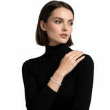 Woman with a dark bob and black turtleneck wearing a silver-tone bracelet, with her opposite hand across her shoulder.