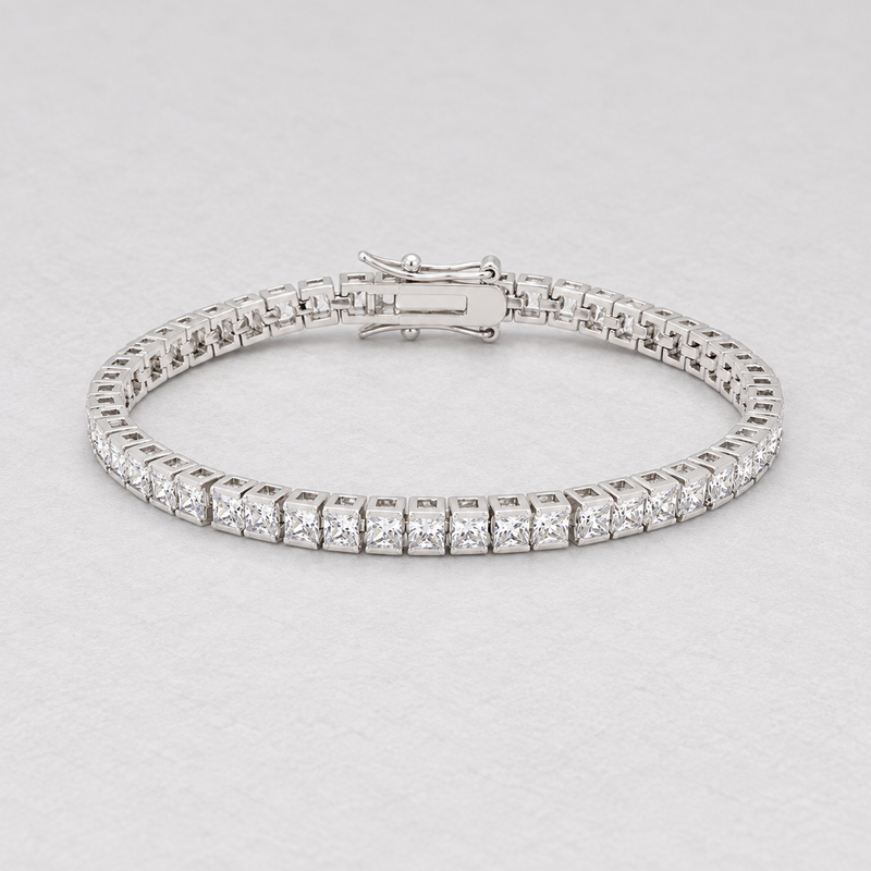 Full oval silver-tone bracelet with clear square stones on a pale textured surface.