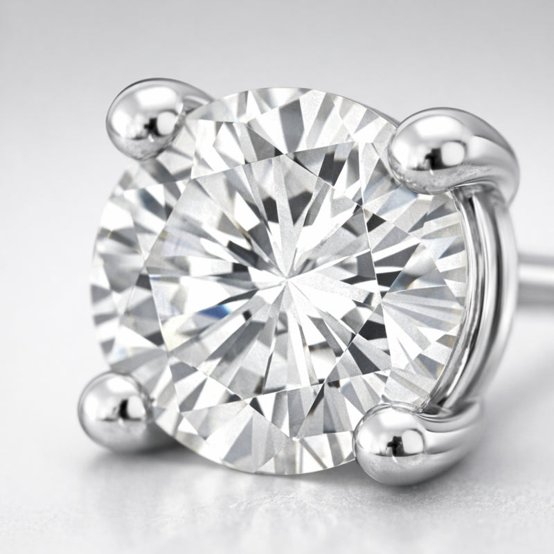 Detailed close up of a round silver tone stud earring showcasing the brilliant cubic zirconia stone and smooth four prong metal setting.