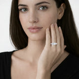Model view showcases a silver tone three stone halo cubic zirconia ring, styled with a tailored black top so the ring sparkles along the fingertips.